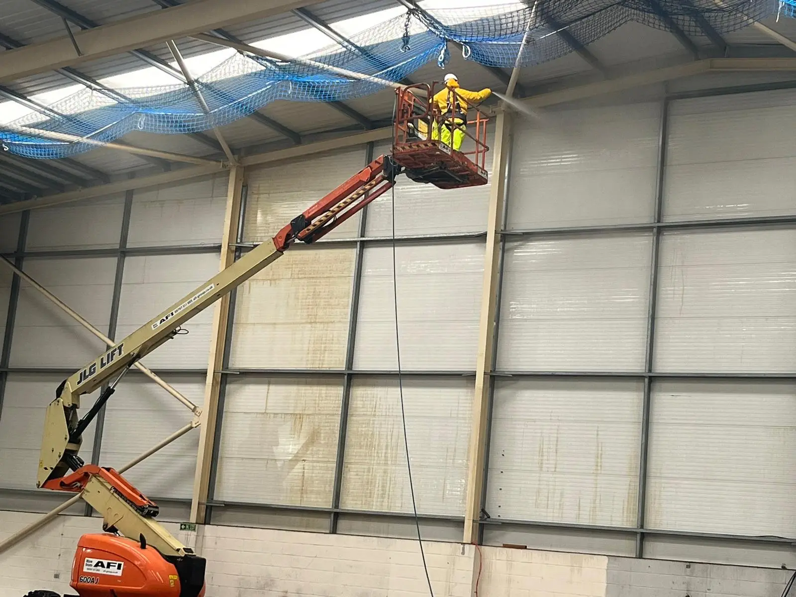 Technician performing high level cleaning on industrial structure