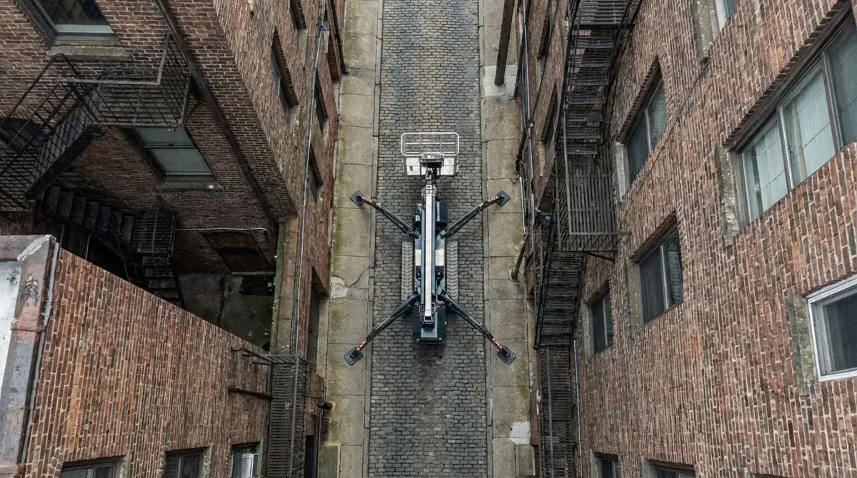 Aerial drone view of spider cherry picker navigating narrow alleyway between buildings