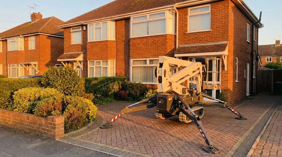 Spider cherry picker with outriggers deployed at residential property in golden hour light